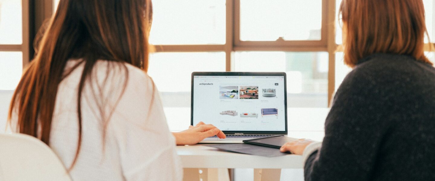 two women talking while looking at laptop computer